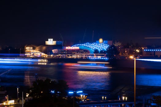 A captivating long exposure of Hamburg's harbor with vibrant blue lights reflecting on the water at night.