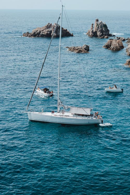 Free Aerial view of sailing boats and rock formations in turquoise waters of Blanes, Spain. Stock Photo