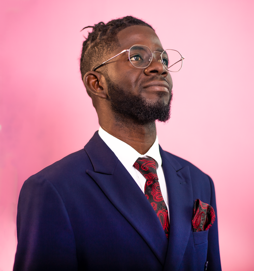 Free Smiling man in a blue suit and glasses against a pink background. Stock Photo
