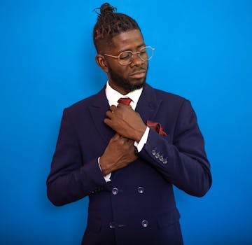 Portrait of an elegant man in corporate attire adjusting his tie in a studio setting.