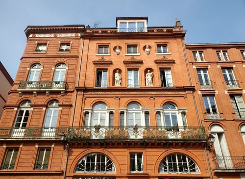 Red brick facade with classical architecture in Place de la Trinité, Toulouse.
