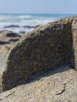 Detailed view of rocky shoreline with ocean waves in the background.