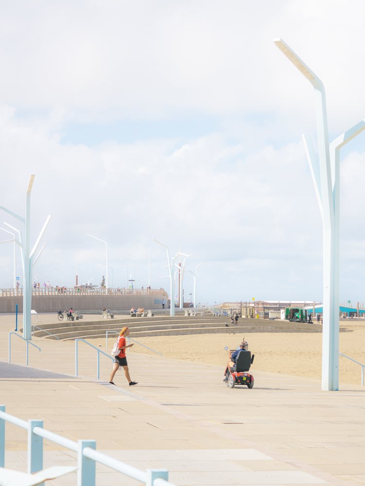 People Walking On Sidewalk By Beach