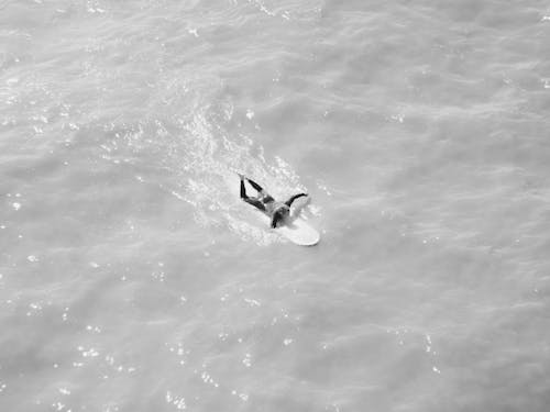 Grayscale Photography of a Person Surfing on the Sea Water