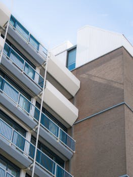 Low angle view of a modern apartment building with blue balconies against a clear sky.