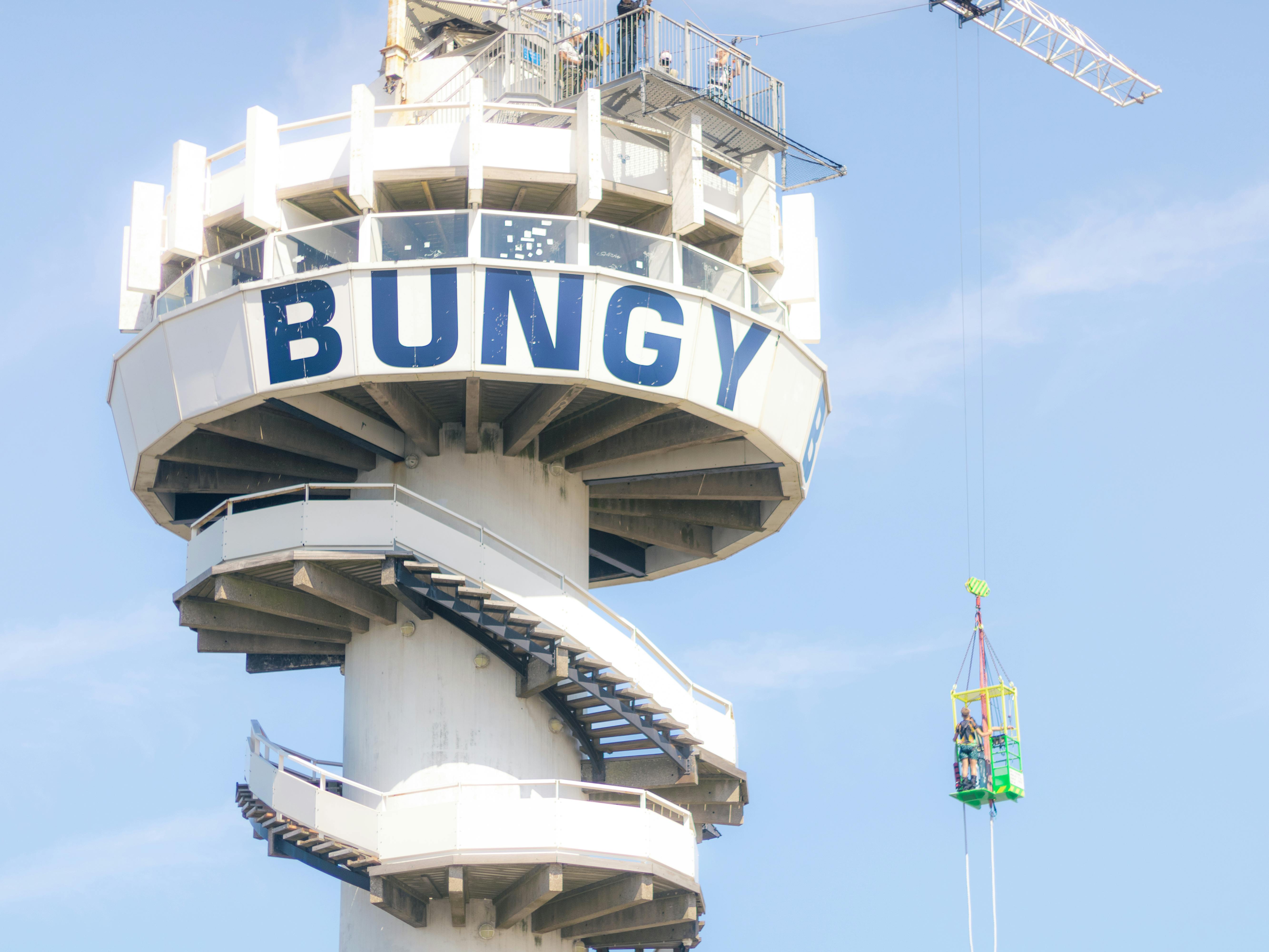 High-angle shot of a bungee jumping platform with spiral stairs against a clear blue sky.