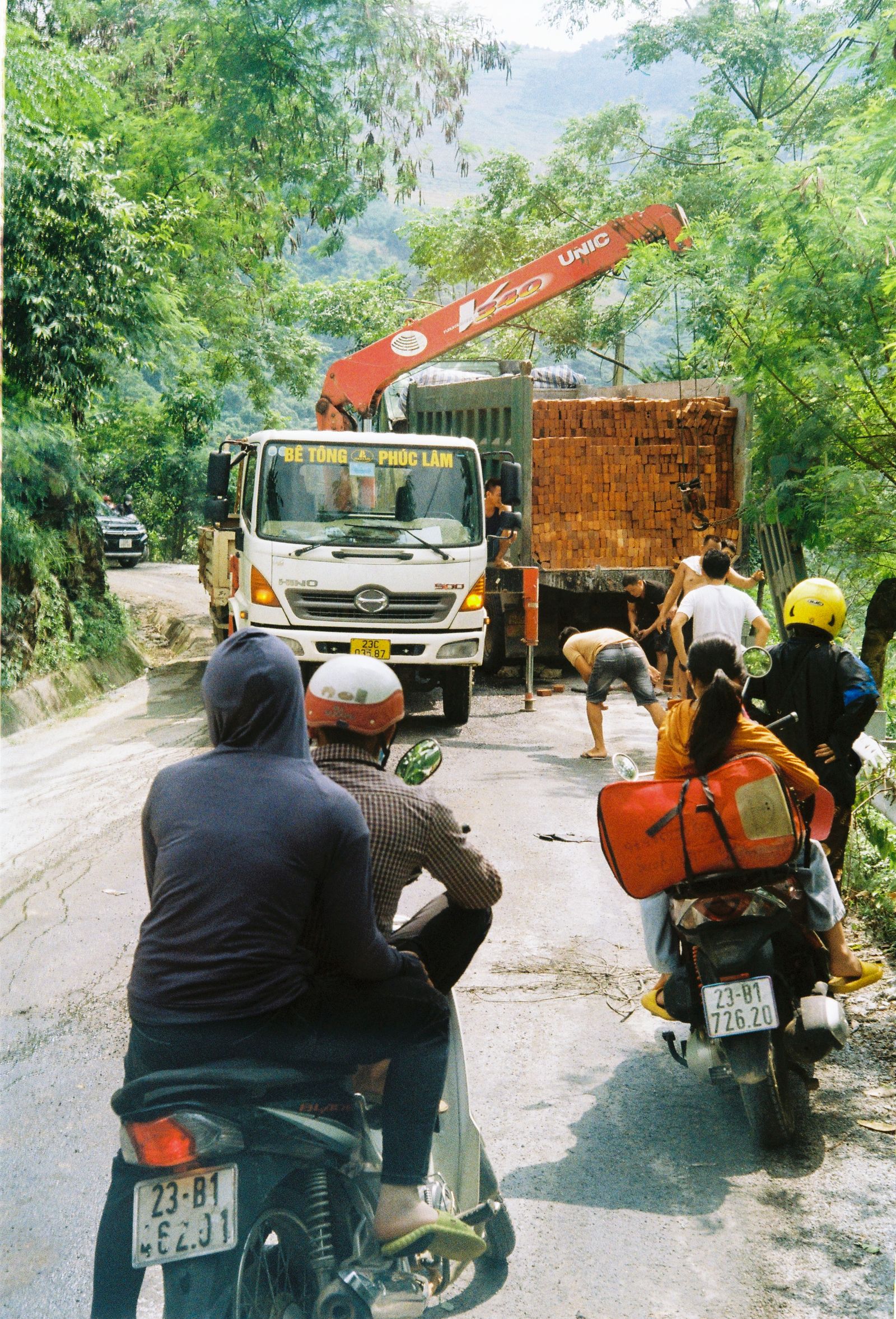 Motorcyclists waiting on a narrow mountain road showing why safe logistics matter on the Ha Giang Loop