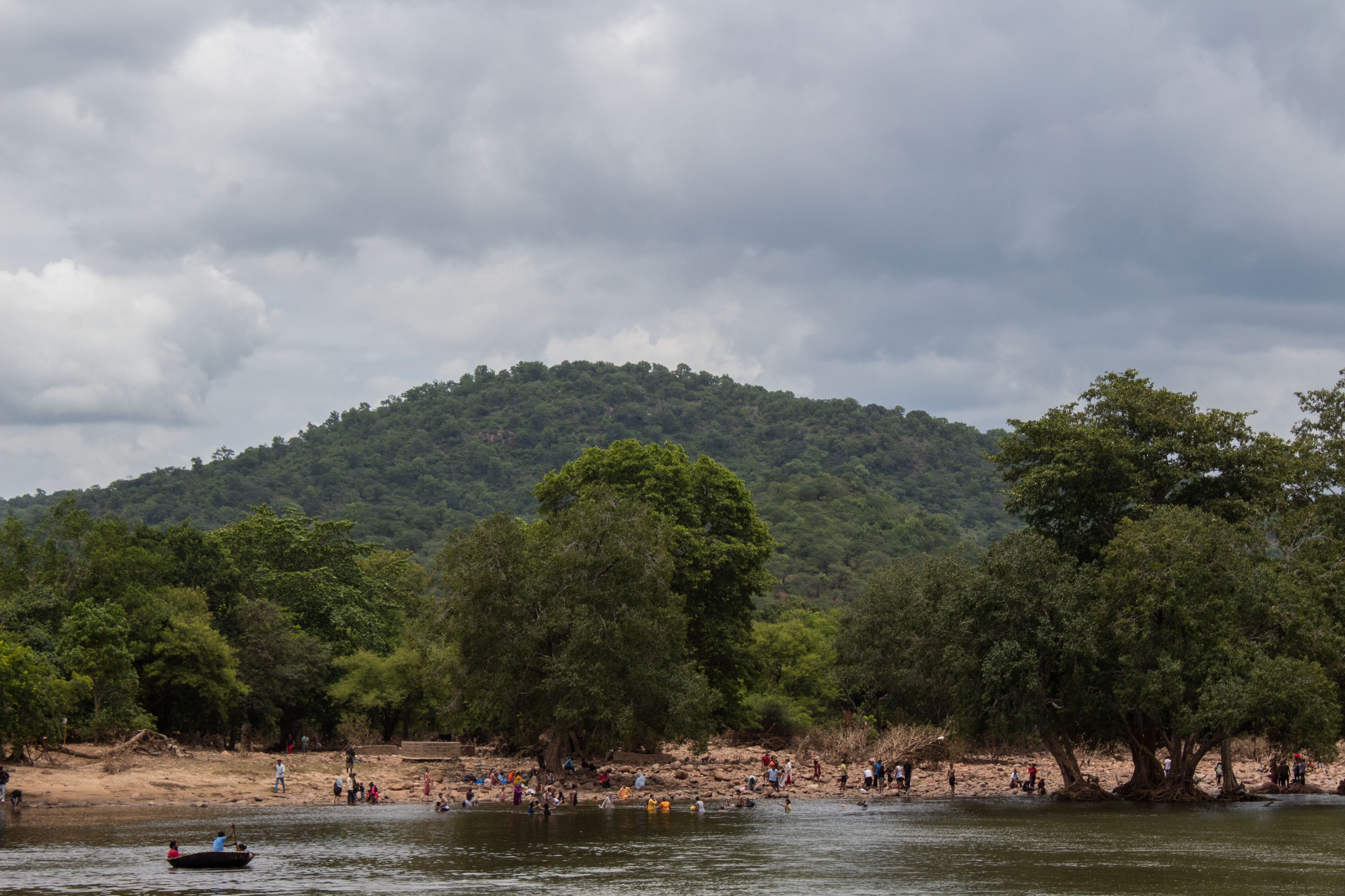 A picturesque view of a riverbank, hills, and forest in Sangama, India.