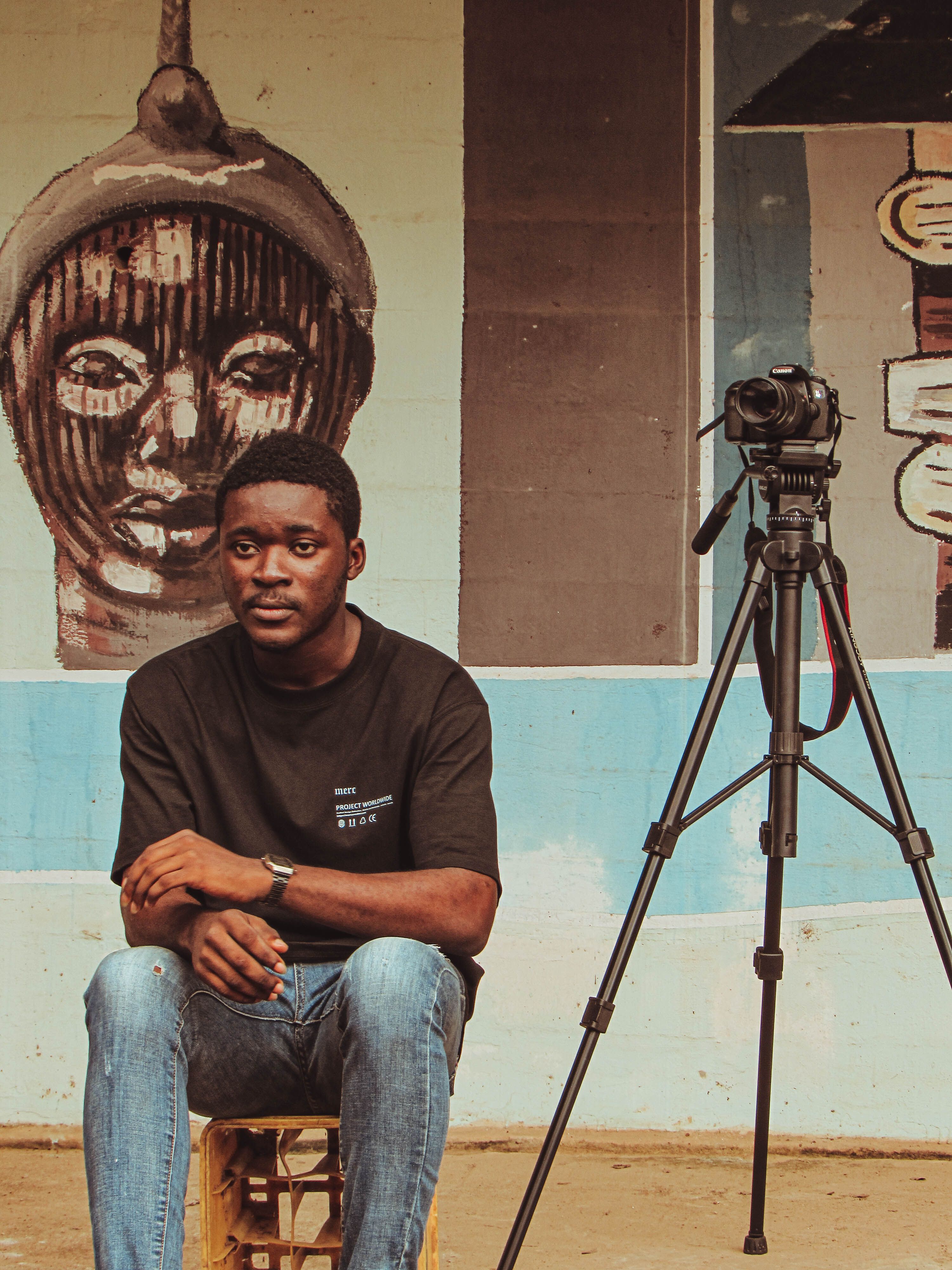 Young African man with camera and mural background in Ife, Nigeria.