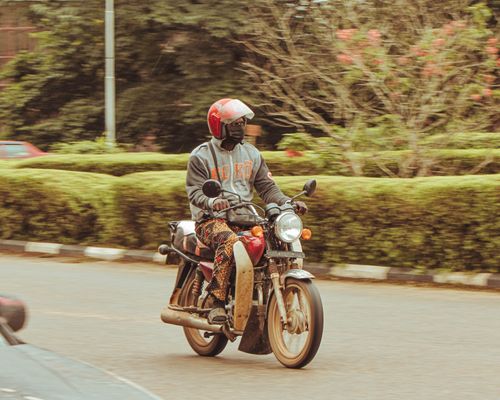 Free A motorcyclist wearing a helmet rides through the streets of Ife, Nigeria, showcasing local life. Stock Photo