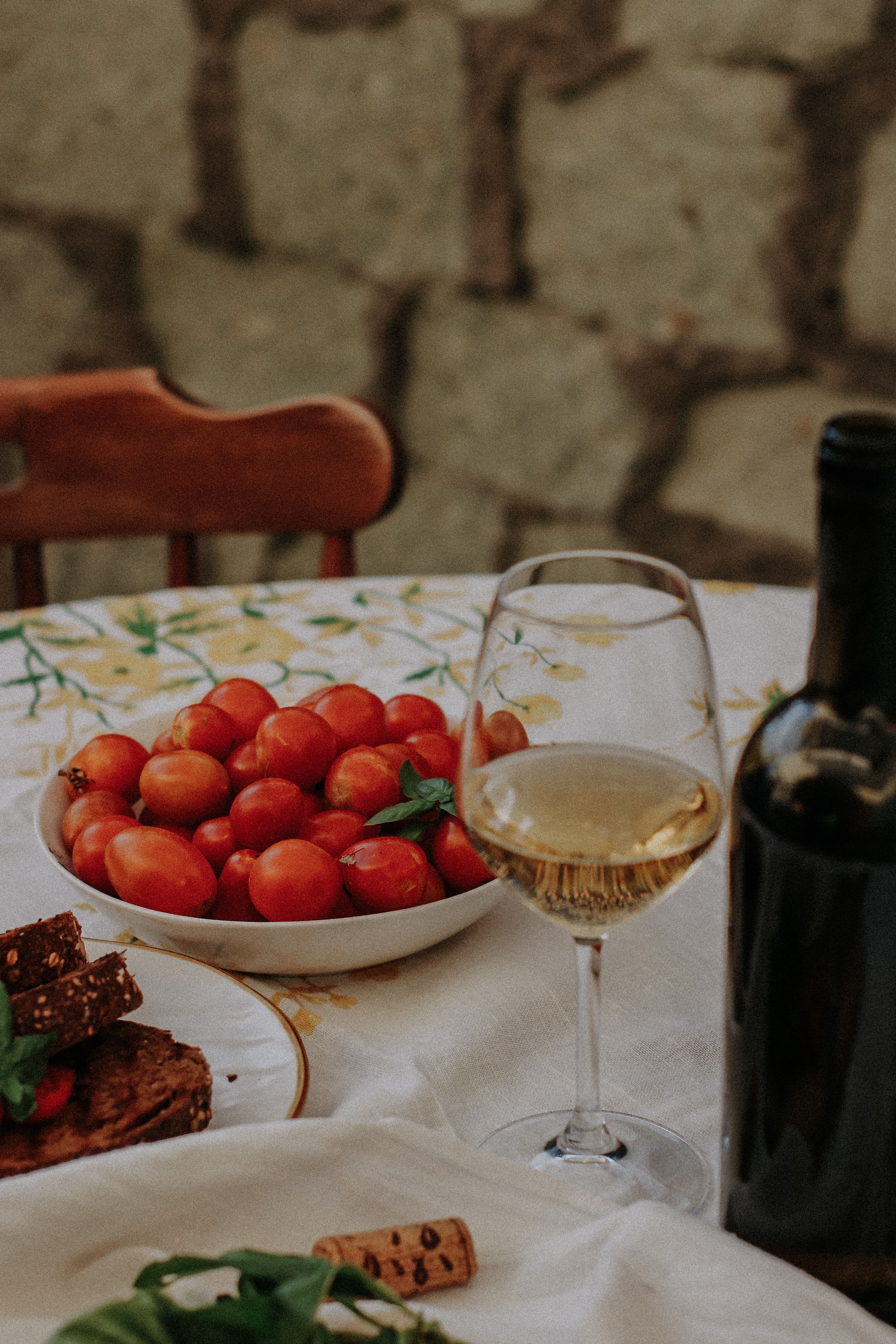 Close-up of a table setting with wine glass, wine bottle, and fresh tomatoes, perfect for dining themes.