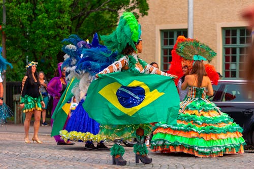 People in Costumes Holding a Brazilian Flag and Celebrating on the City Street