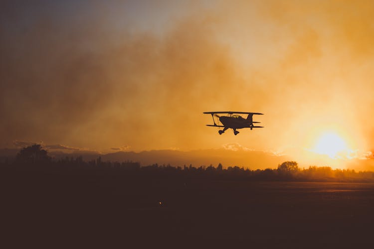 Silhouette Of Cessna Plane Flying Under Golden Sky