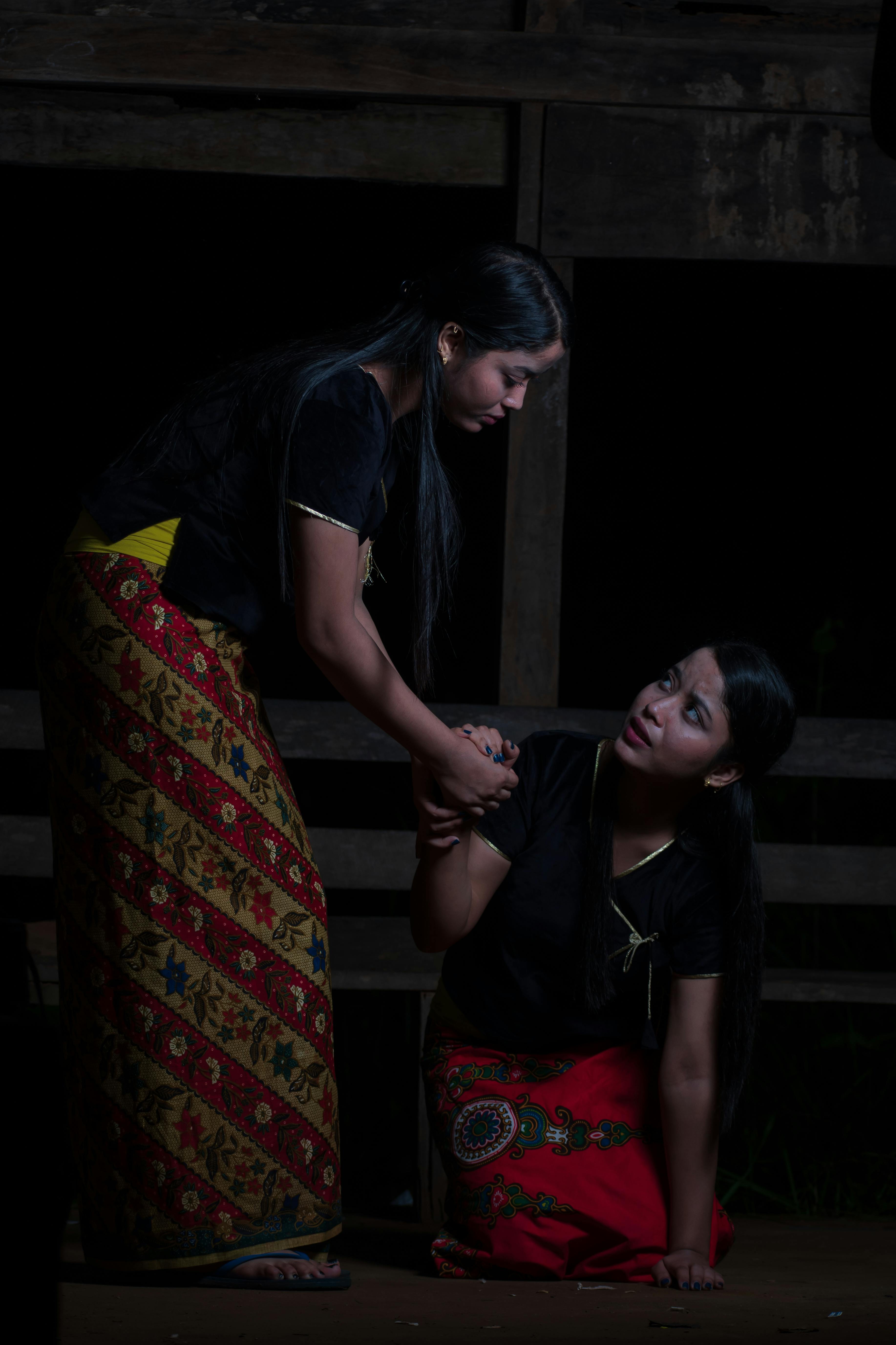 Free Two women in traditional attire performing a dramatic scene on stage. Stock Photo