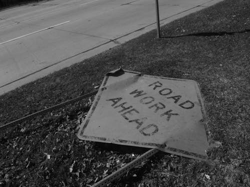 Grayscale Photo of a Road Sign on the Ground