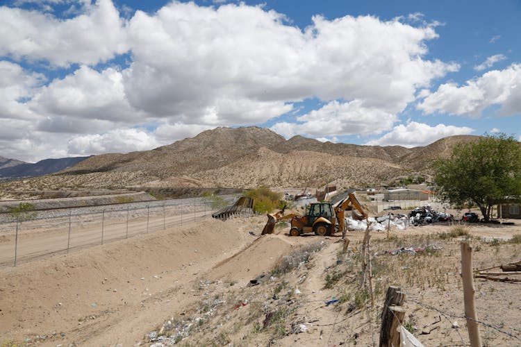 Excavator Near Fence And Dirt Road