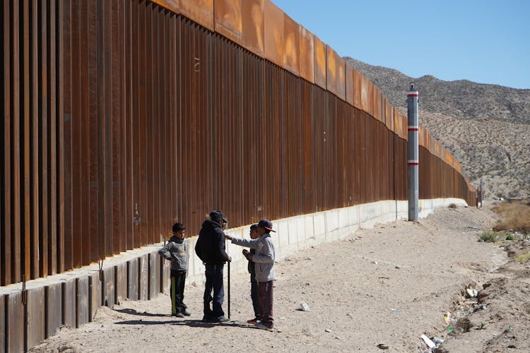 Children Standing Next To Borderline Wall