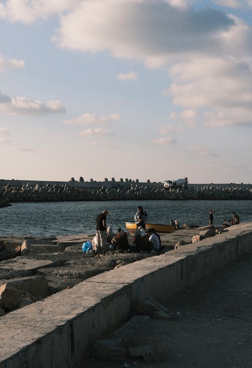 People Sitting on Rocks on the Shore 