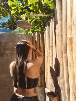 A woman showering outdoors under natural light, enjoying a refreshing moment.