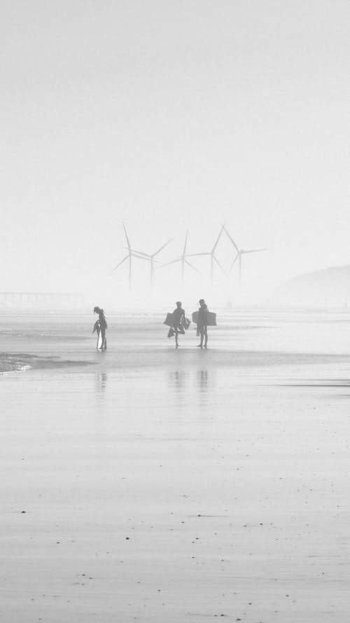 Grayscale Photo of People Walking on Beach