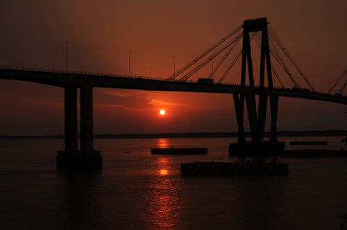 Free Dramatic sunset over General Manuel Belgrano Bridge with vibrant reflections in Corrientes, Argentina. Stock Photo