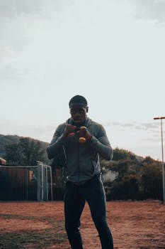 African American man working out with dumbbells outdoors, emphasizing fitness and strength.