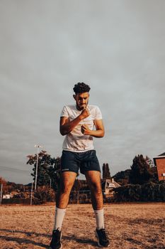 A man performs shadow boxing outdoors in a sunny summer day, showcasing fitness and agility.
