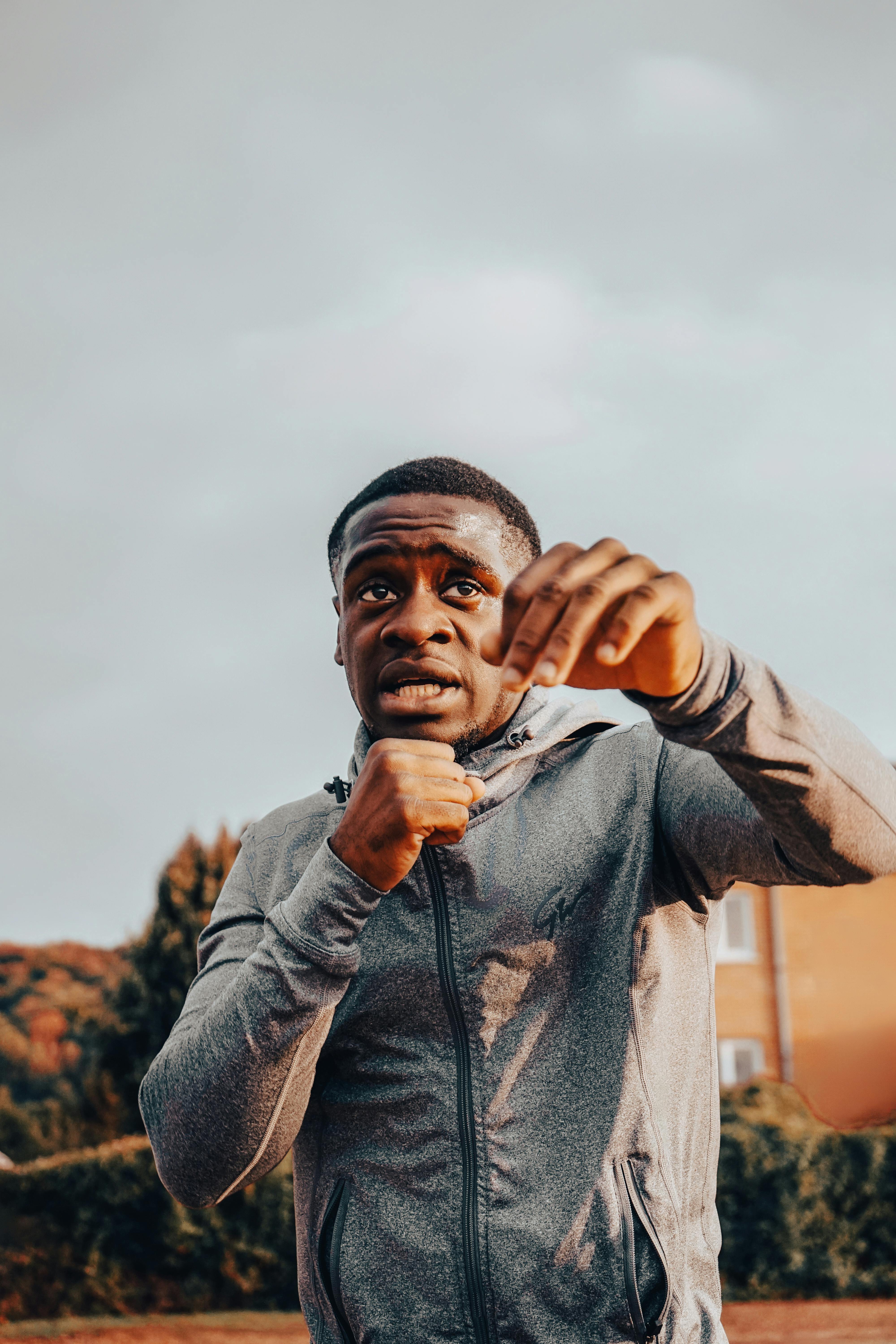 African American man in athletic wear practicing boxing outdoors during the day.