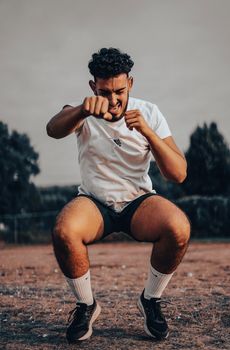 Energetic young man in sportswear practicing boxing moves outdoors.
