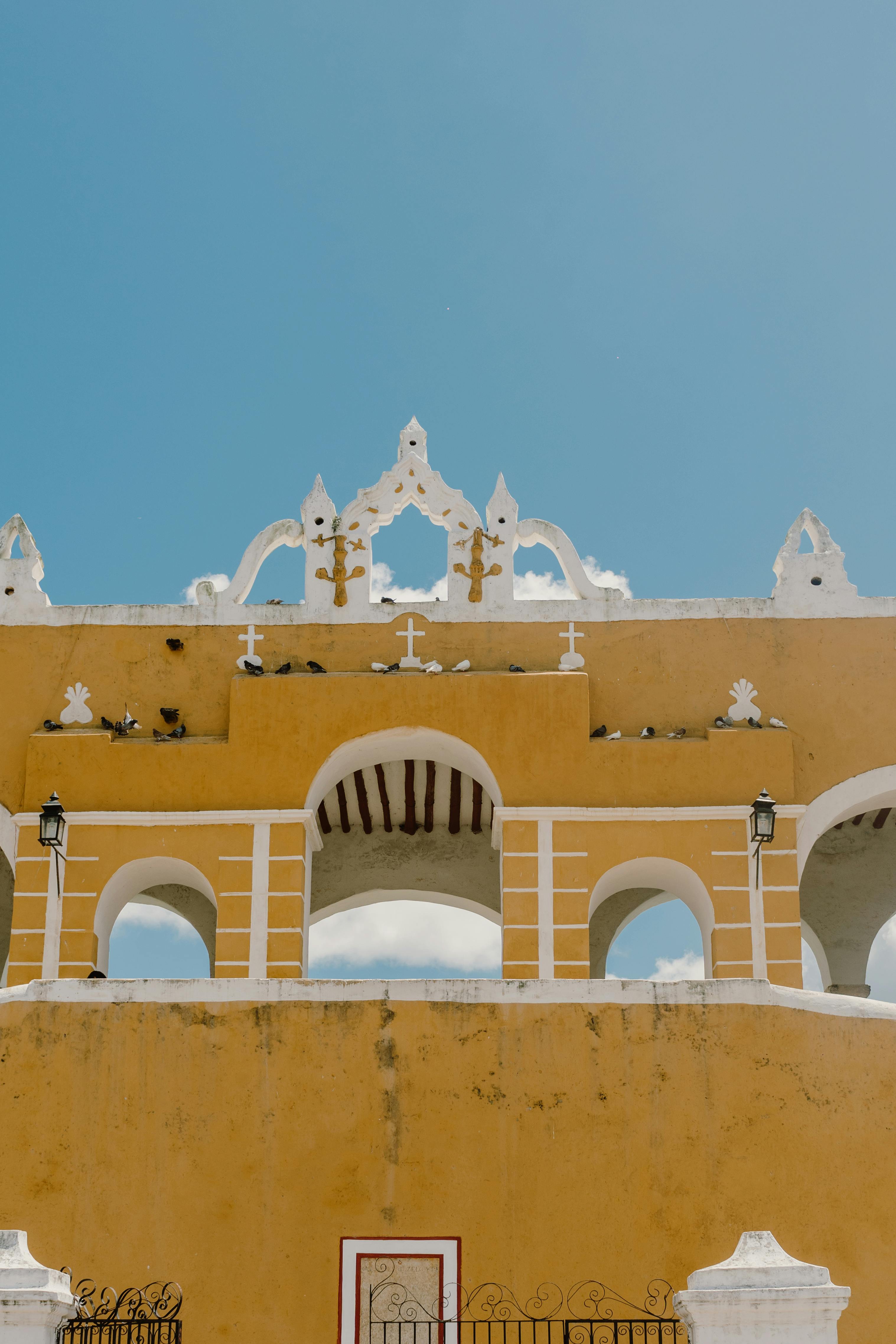 Capture of yellow church facade with ornate details under a clear blue sky in Izamal, Mexico.