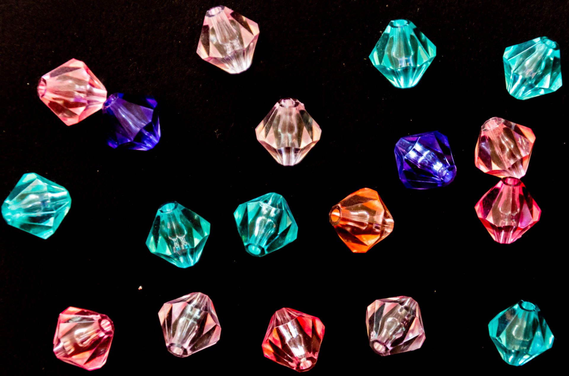 Vibrant collection of acrylic beads in various colors on a black background, ideal for craft and jewelry design.