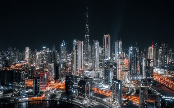 Stunning aerial view of Dubai's illuminated skyline at night with the Burj Khalifa prominently visible.