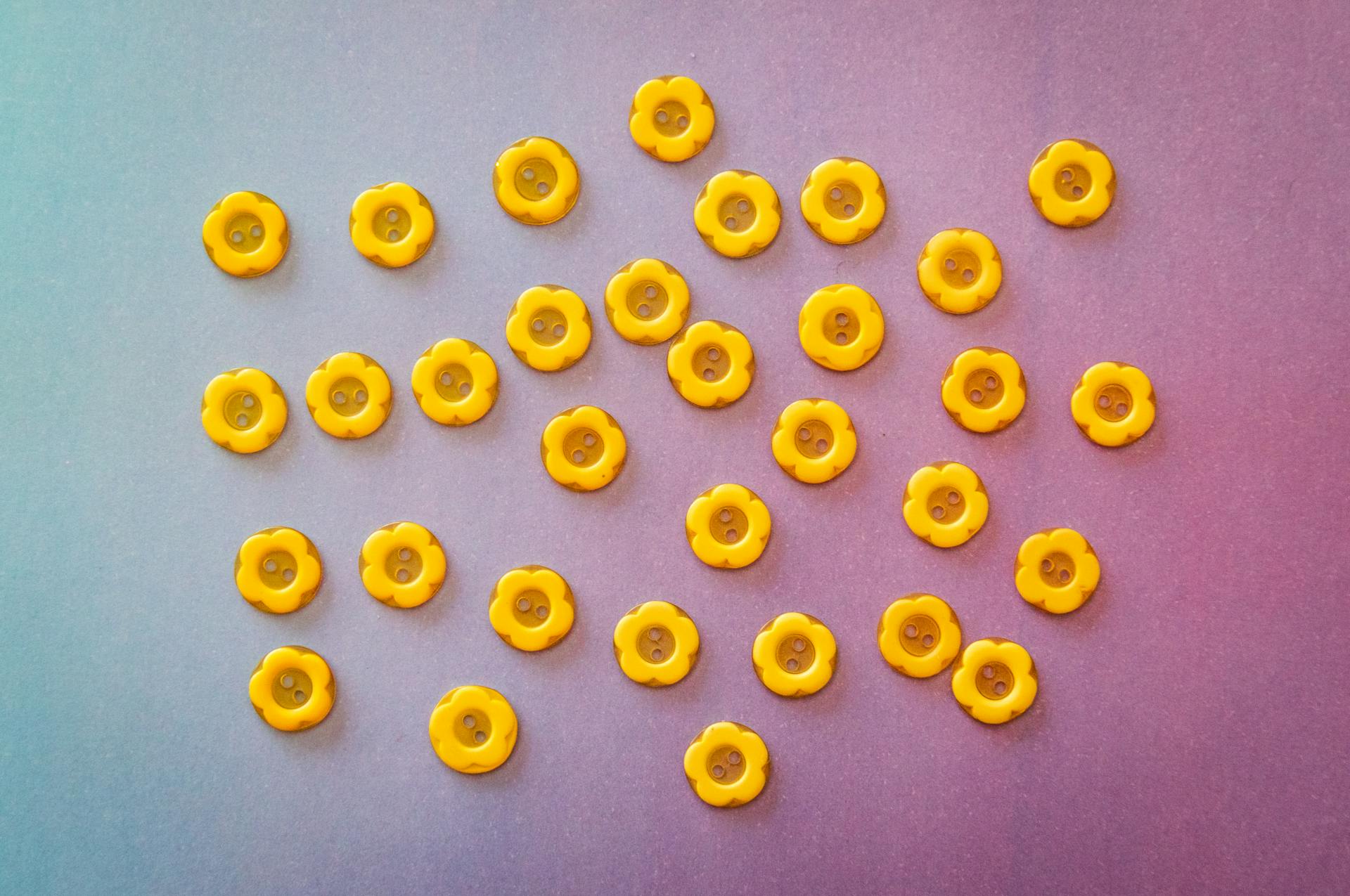 Vibrant yellow flower-shaped buttons arranged on a colorful gradient backdrop.