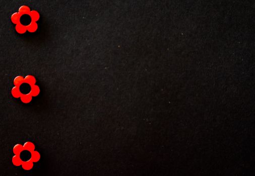 Three red flower beads arranged on a dark, textured background.