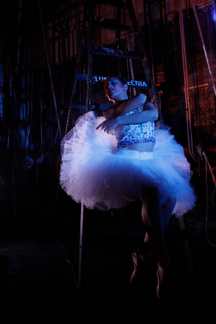 A Ballerina Wearing White Tutu Dress Dancing On A Stage Near A Ladder