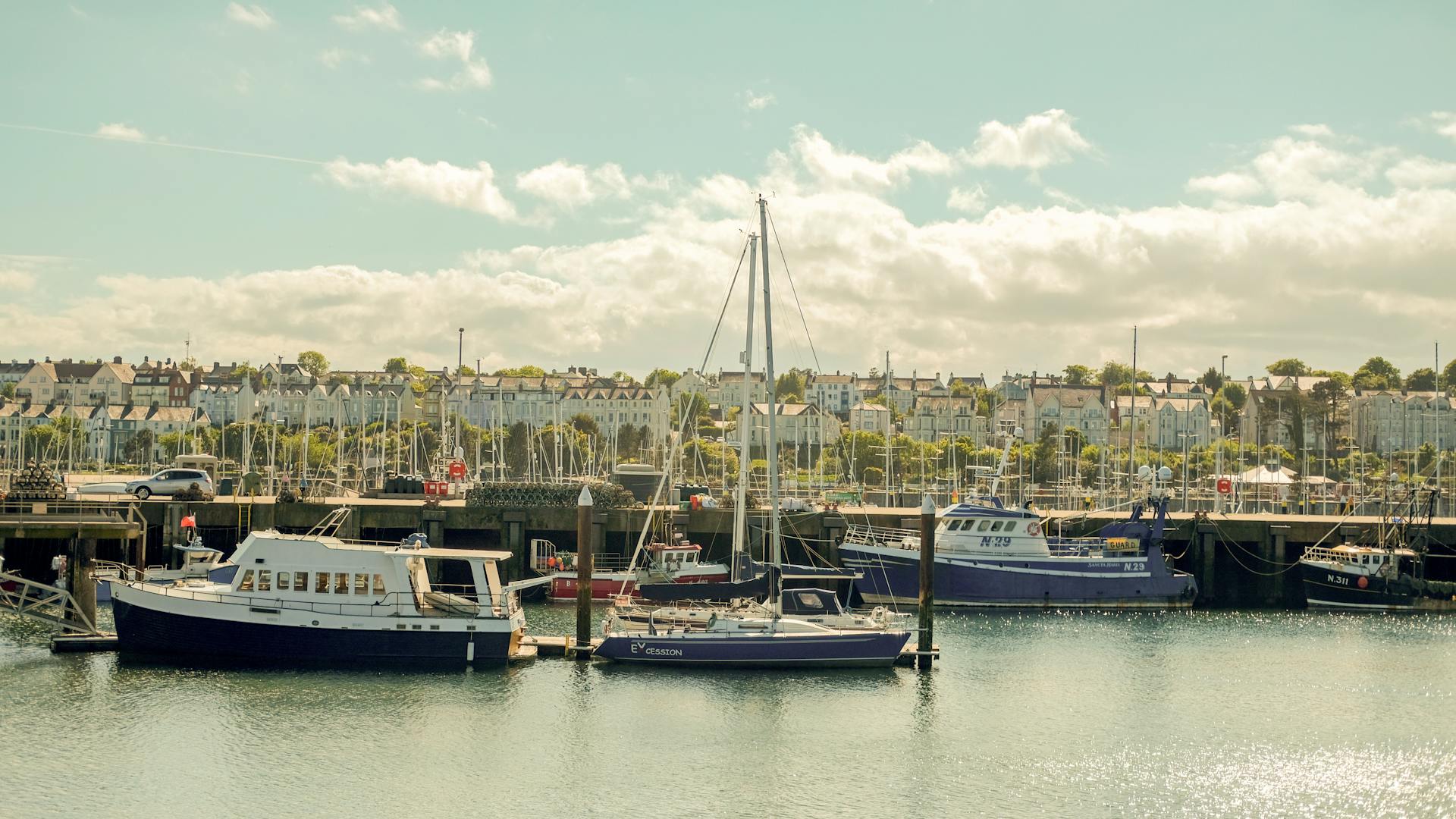 Explore Bangor, Wales with this vibrant marina scene featuring moored boats and urban architecture.