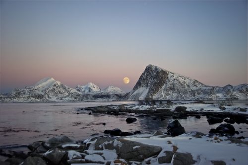 Free Stunning view of snowcapped mountains and a full moon over a frozen lake during twilight. Stock Photo