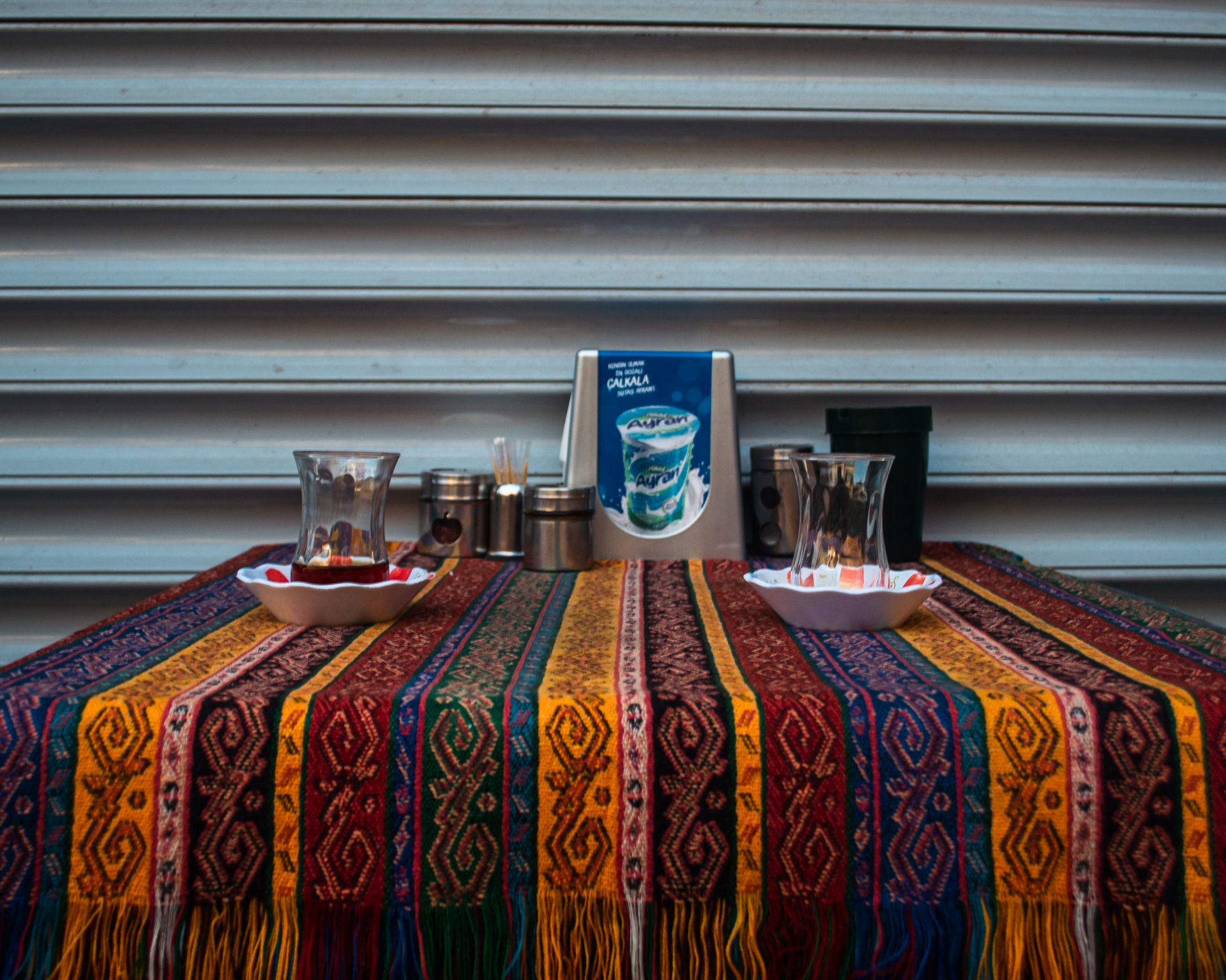 Vibrant outdoor table setup with colorful patterned tablecloth and tea glasses for a cultural dining experience.