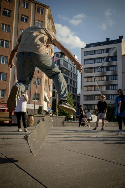 Free Skateboarder performing a flip trick in a lively Eskişehir street. Stock Photo