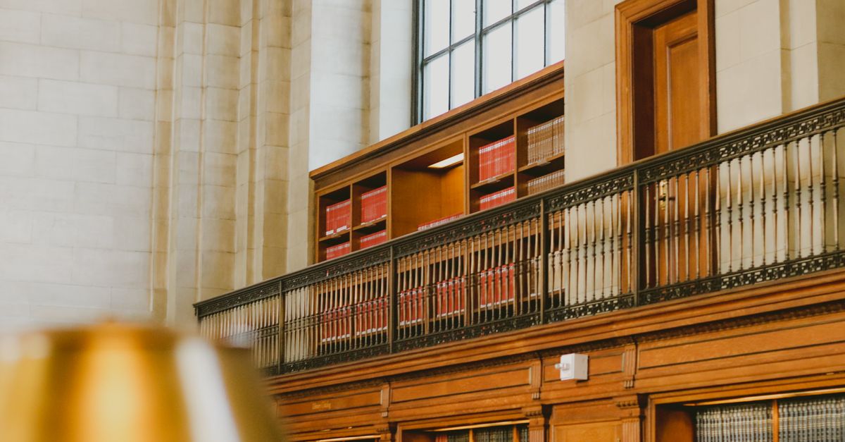 A warm and inviting library interior featuring classic wooden shelves and a railing.