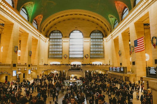 A bustling scene at Grand Central Terminal with festive decorations and a large crowd.