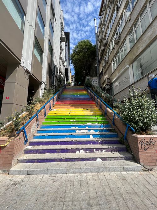 Free Vividly painted urban stairway with rainbow colors between city buildings. Stock Photo
