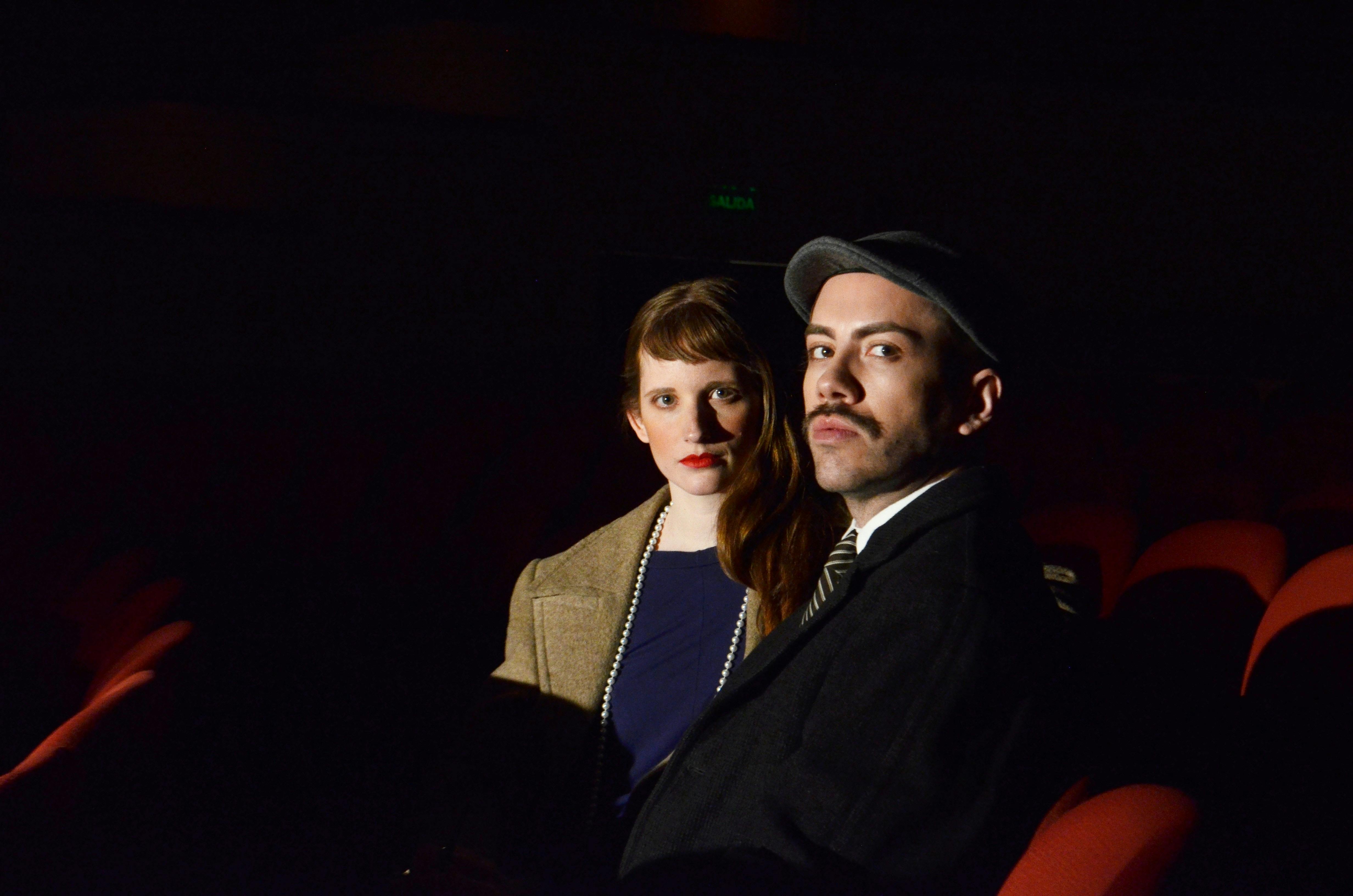 Free A man and woman sitting in a dimly lit theater, adding a vintage touch. Stock Photo