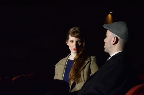 Free A couple in vintage attire seated in a dimly lit cinema setting, evoking nostalgia. Stock Photo