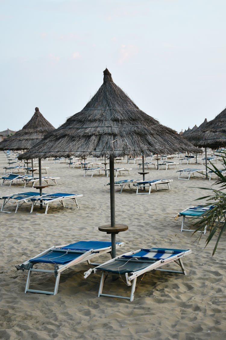 Beach Lounge Chairs And Nipa Huts On The Shore Of A Beach