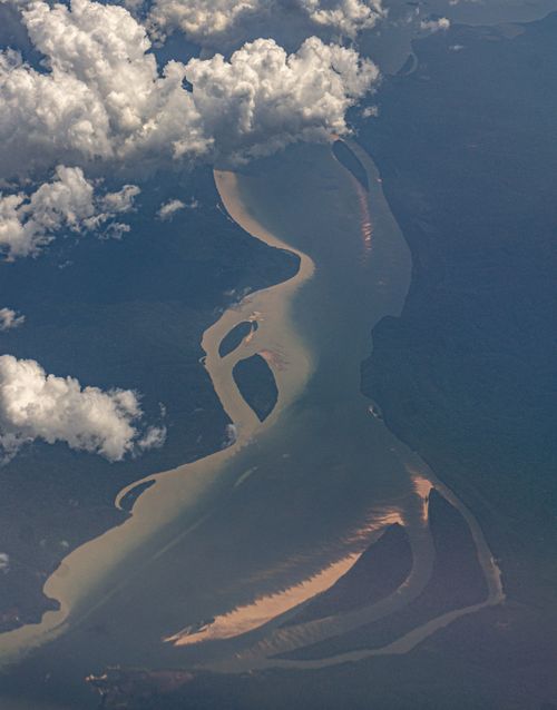 Free Stunning drone shot capturing a river winding through lush woodland beneath clouds. Stock Photo