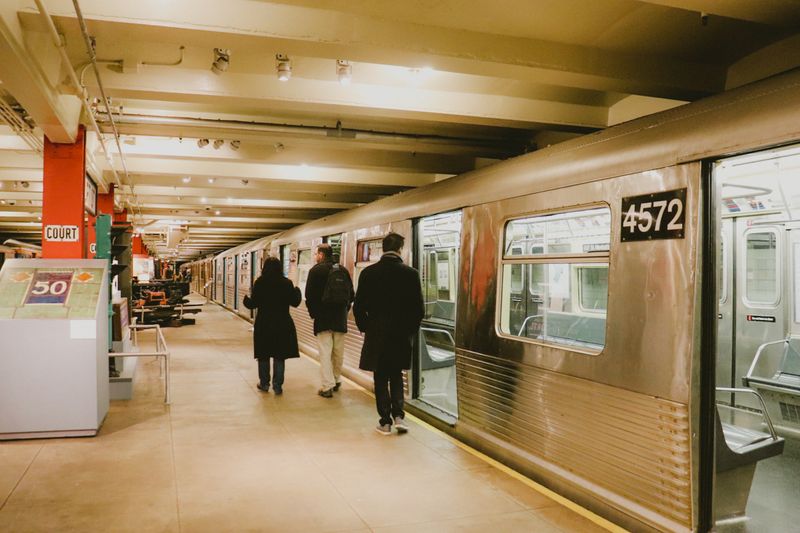 Passengers walking on a subway platform beside a train, showcasing public transportation in a bustling urban environment.