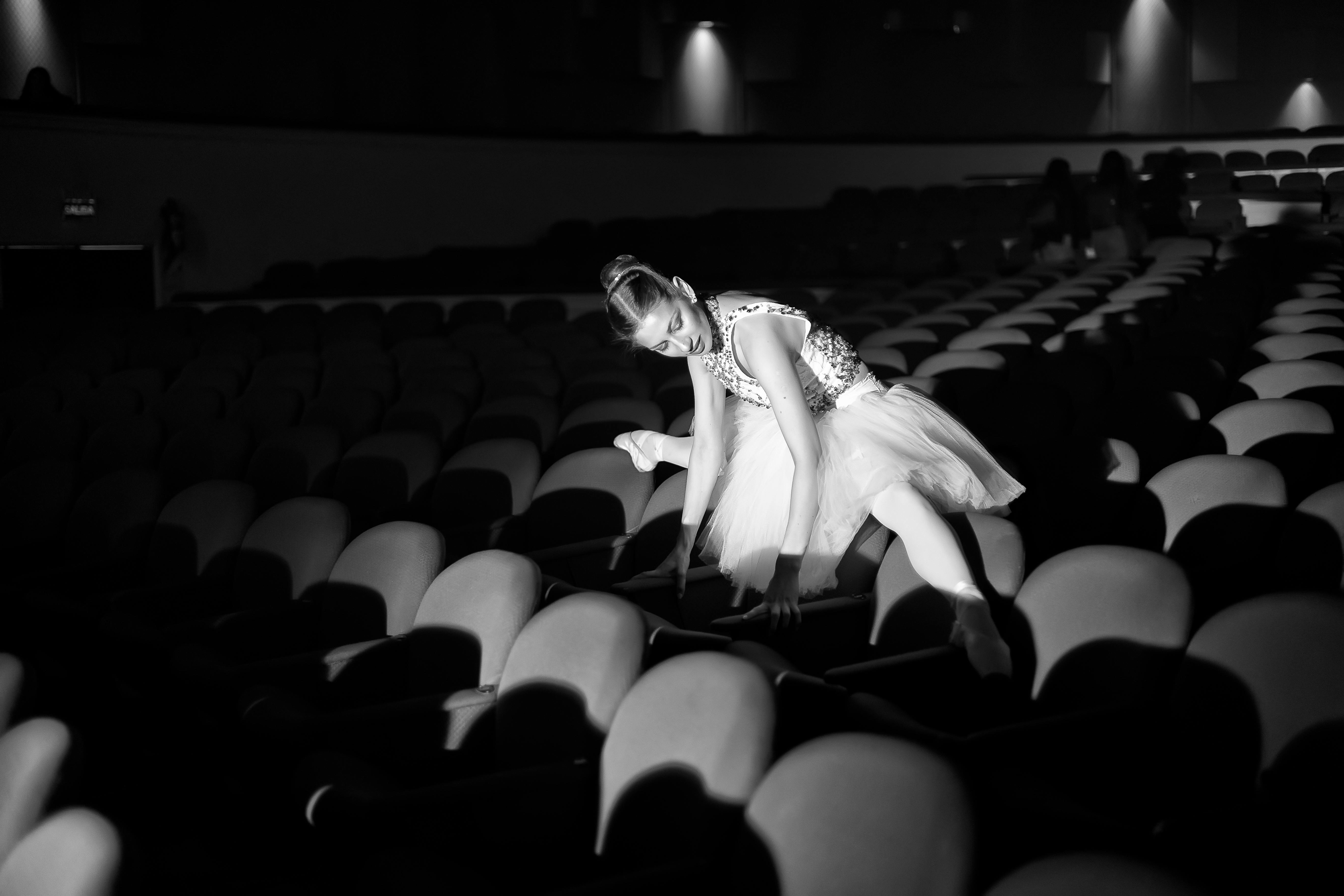 Free A captivating black and white photo of a ballerina performing on theater seats. Stock Photo