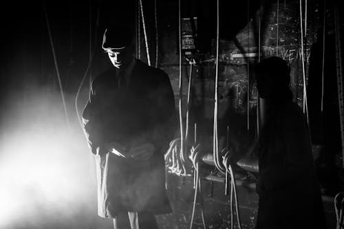 Black and White Photo of a Man Standing by a Construction with Ropes