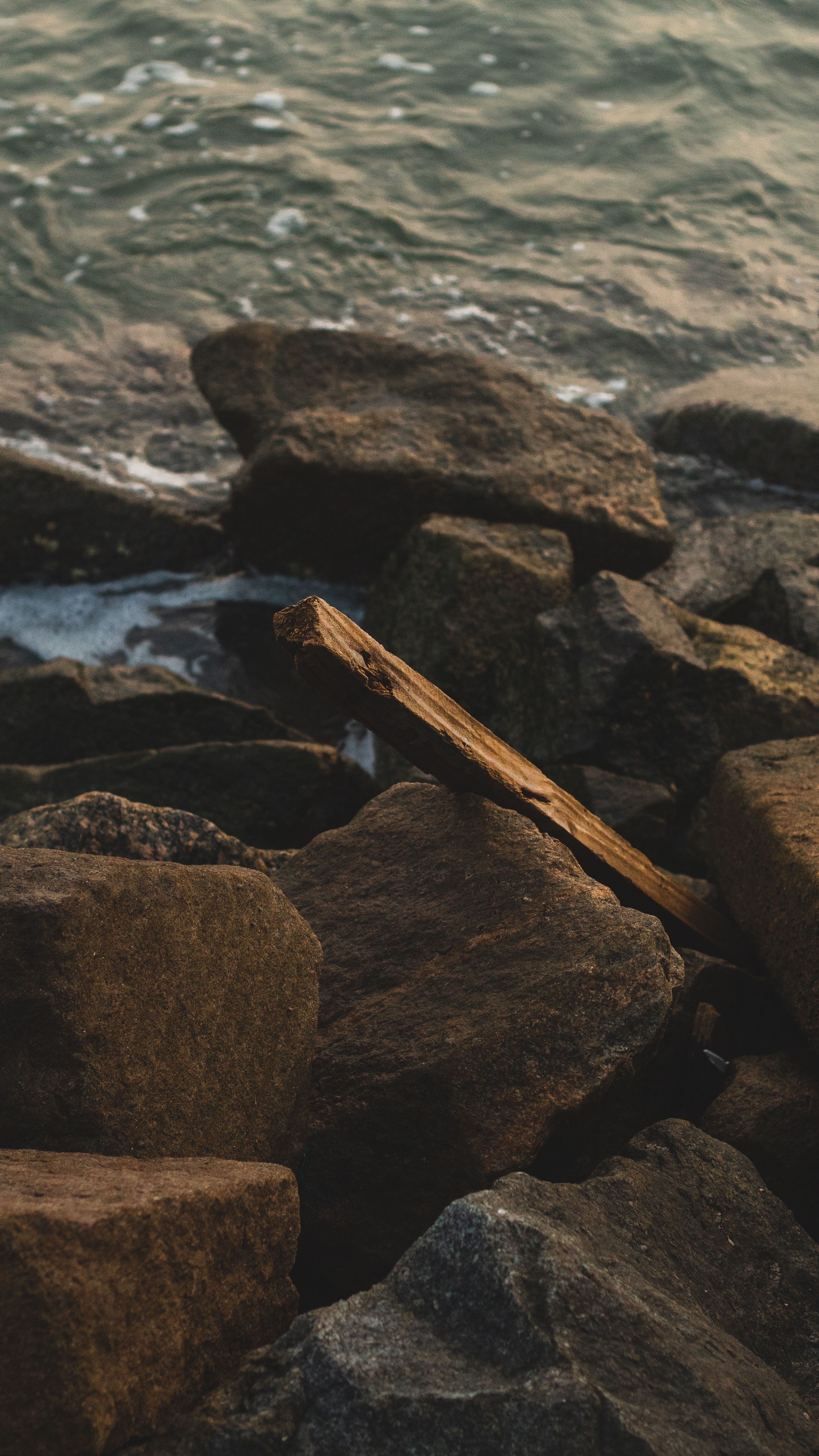 Close-up of rocky shoreline at Santos, Brazil, with ocean waves crashing gently.
